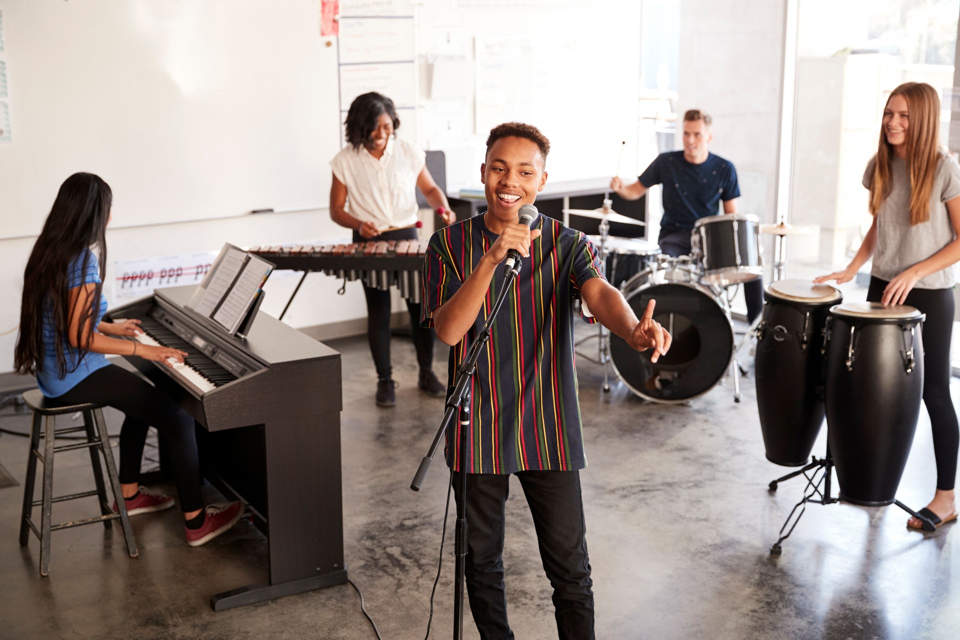 Students At Performing Arts School Playing In Band At Rehearsal With Teacher